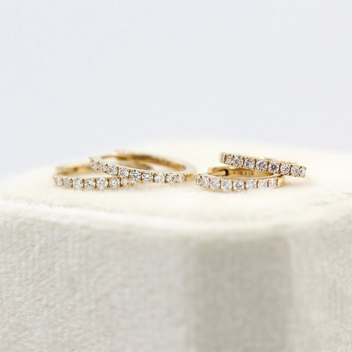 The 14mm and 12mm Diamond Huggies in yellow gold atop a tan velvet ring box