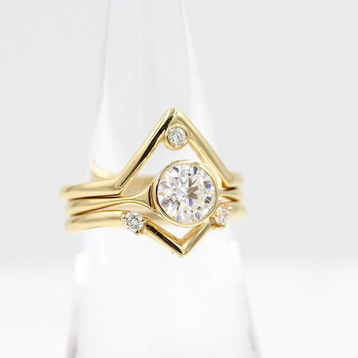 The Double Diamond V-Band in yellow gold stacked with the Stevie round in yellow gold and the single diamond v-band in yellow gold on a plastic cone