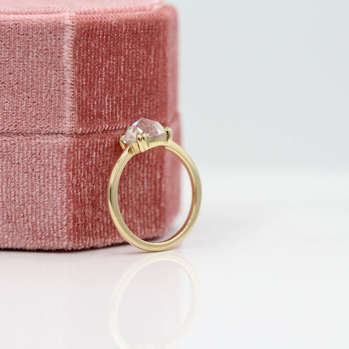 The Nora ring (round) in yellow gold leaning against a pink velvet ring box