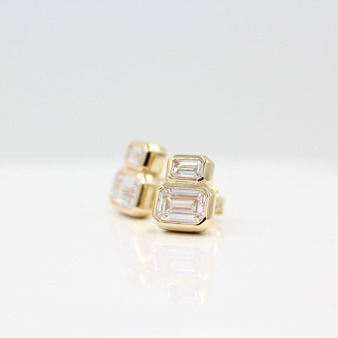 Emerald-Cut Diamond Two-Stone Earrings in yellow gold with 3ct total weight against a white background