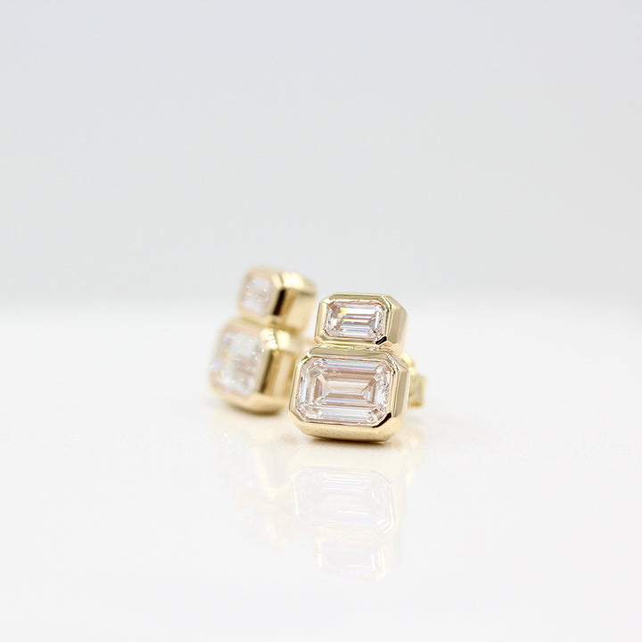 Emerald-Cut Diamond Two-Stone Earrings in yellow gold with 3ct total weight against a white background