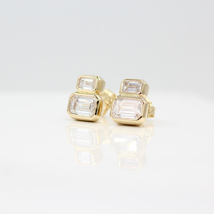 Emerald-Cut Diamond Two-Stone Earrings in yellow gold with 3ct total weight against a white background