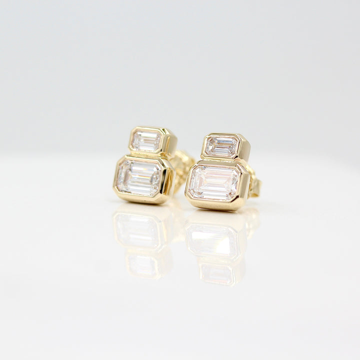 Emerald-Cut Diamond Two-Stone Earrings in yellow gold with 3ct total weight against a white background