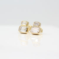 Emerald-Cut Diamond Two-Stone Earrings in yellow gold with 3ct total weight against a white background