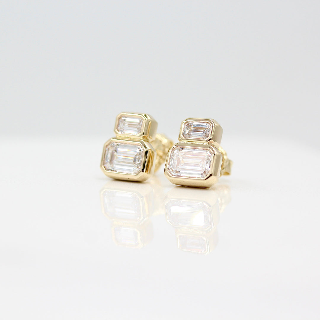 Emerald-Cut Diamond Two-Stone Earrings in yellow gold with 3ct total weight against a white background