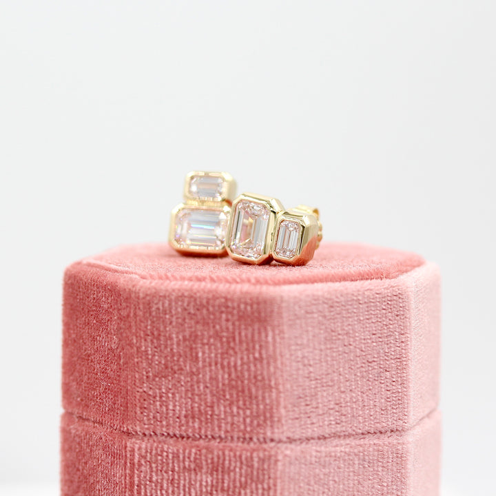 Emerald-Cut Diamond Two-Stone Earrings in yellow gold with 3ct total weight atop a pink velvet ring box