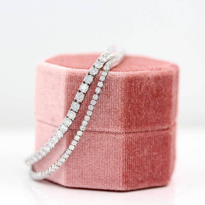 The Classic Lab Grown Diamond Tennis Bracelet in White Gold with 2ct pictured with the Classic Lab Grown Diamond Tennis Bracelet in White Gold with 6ct draped over a pink velvet ring box