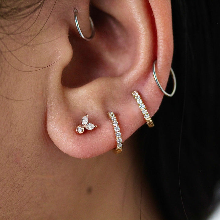 The Sophia earrings in rose gold modeled on an ear with the 12mm and 10mm Diamond Huggies in yellow gold