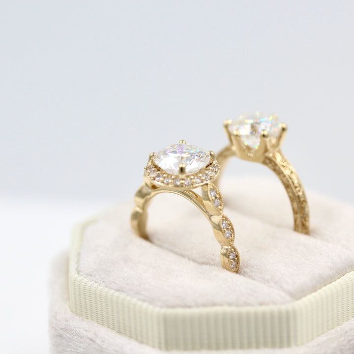 The isla ring round in yellow gold in a white velvet ring box next to the kathleen ring in yellow gold