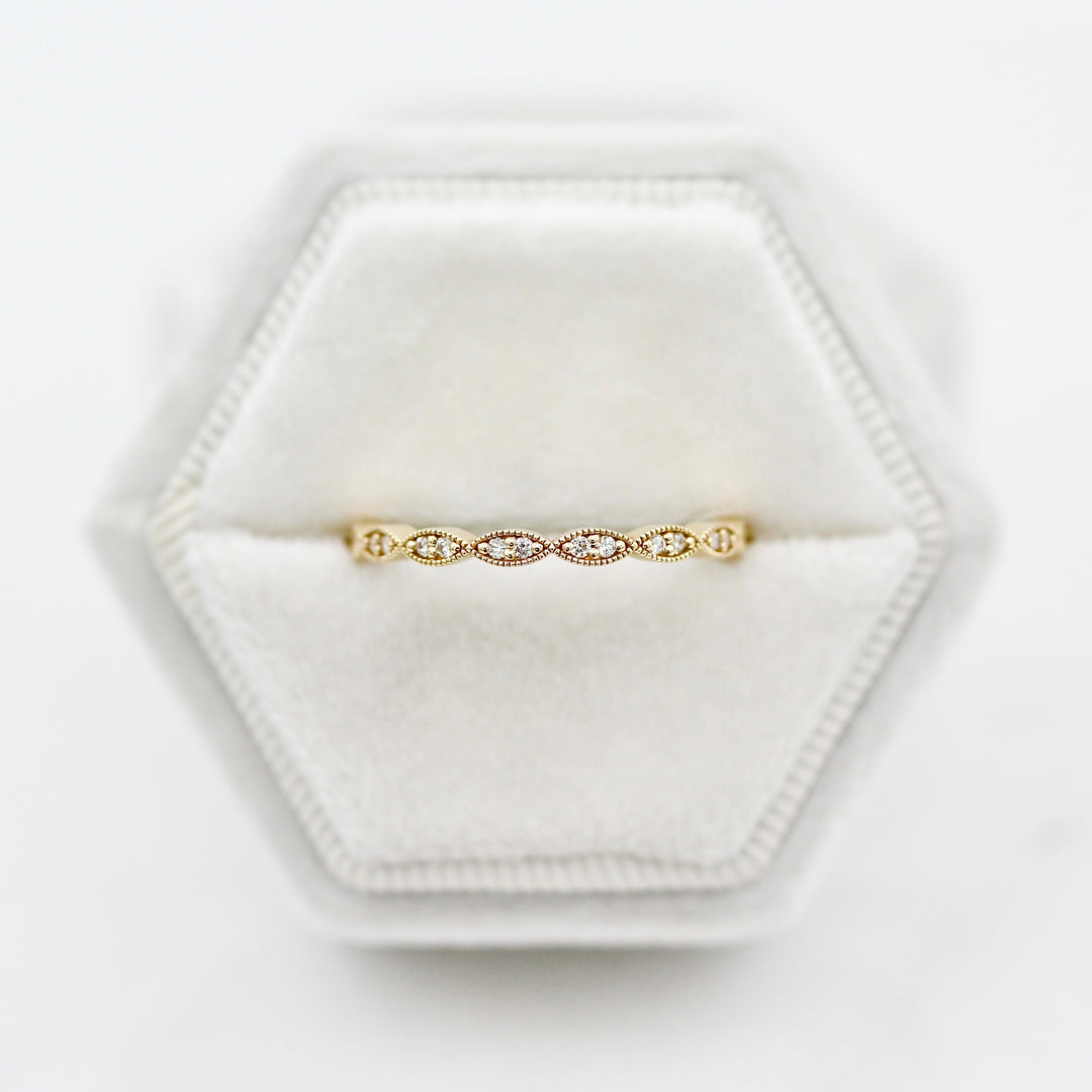 The Isla Wedding Band with twisty milgrain and round diamond accents in yellow gold featured in a white velvet ring box