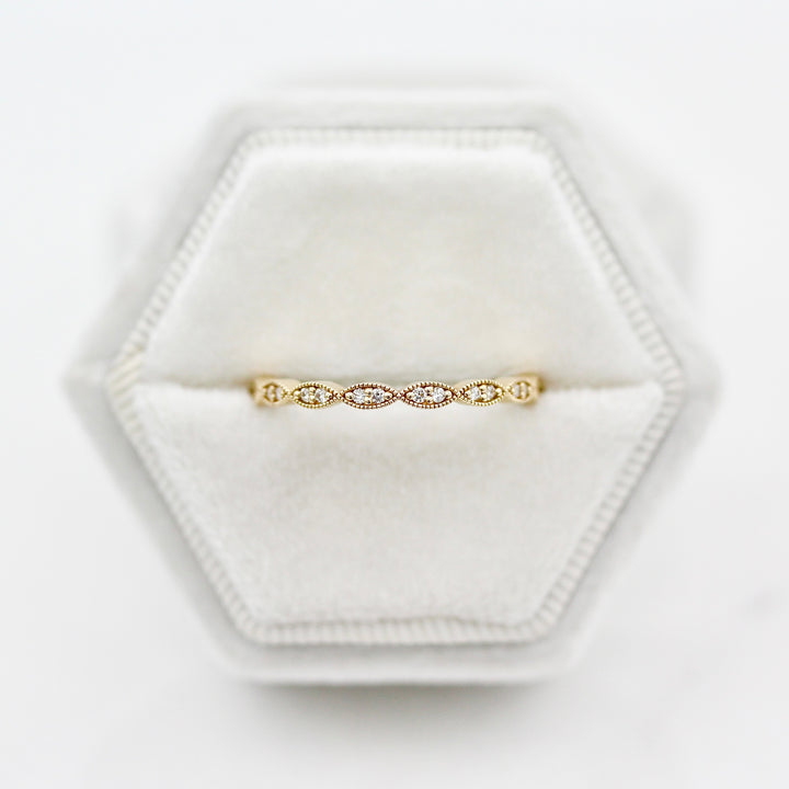 The Isla Wedding Band with twisty milgrain and round diamond accents in yellow gold featured in a white velvet ring box
