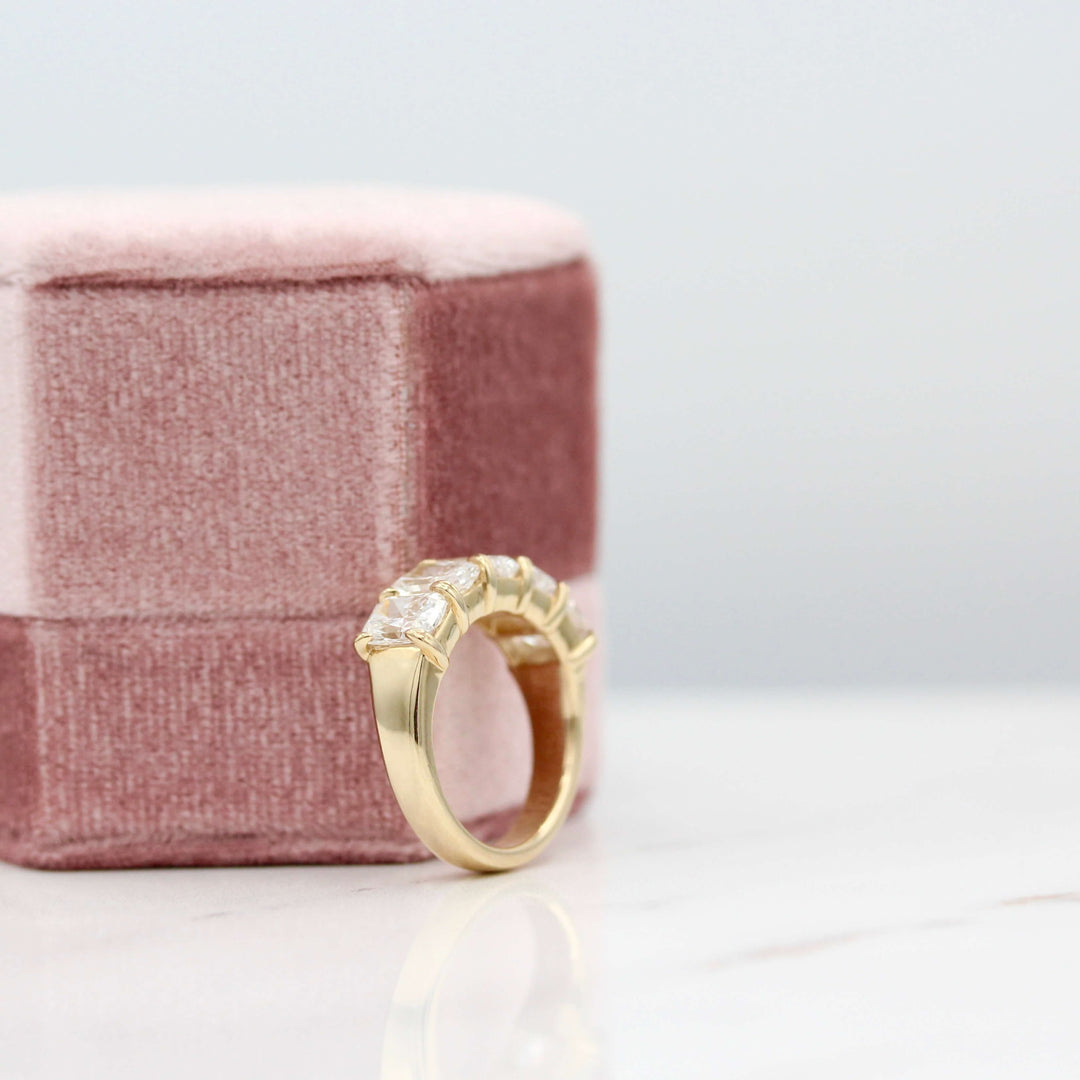 The Keeley Wedding Band in Yellow Gold leaning against a pink velvet ring box