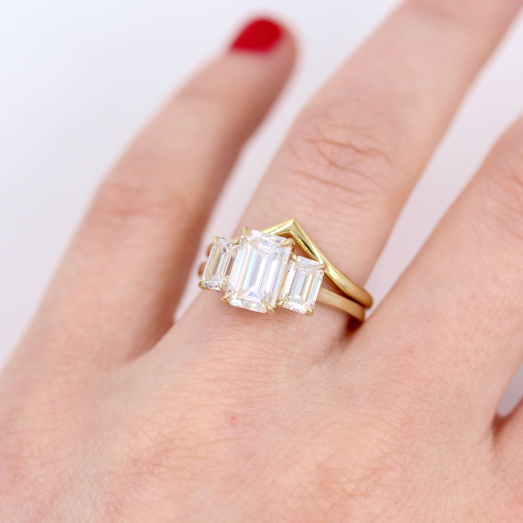The Kendall Hidden Halo Ring in Yellow Gold with Moissanite stacked with the V Wedding Band in yellow gold modeled on a hand
