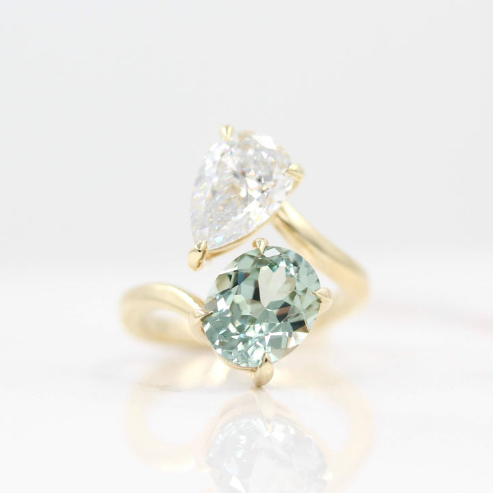 Engagement Ring 14k Yellow Gold Toi Et Moi Diamond and Sage Green Sapphire Bypass Ring in Yellow Gold against a white background