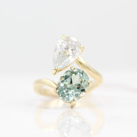 Engagement Ring 14k Yellow Gold Toi Et Moi Diamond and Sage Green Sapphire Bypass Ring in Yellow Gold against a white background