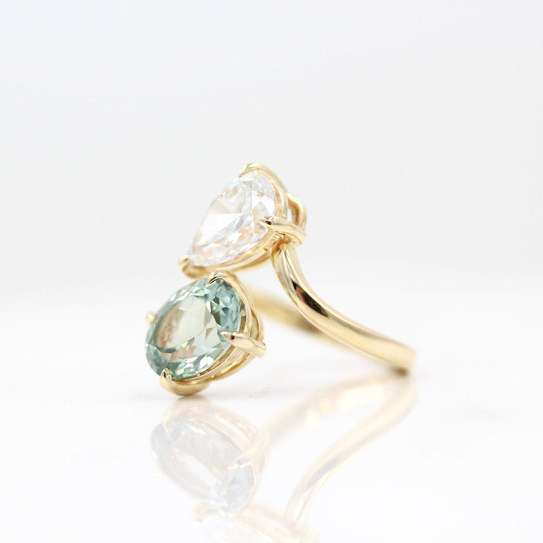 Engagement Ring 14k Yellow Gold Toi Et Moi Diamond and Sage Green Sapphire Bypass Ring in Yellow Gold against a white background