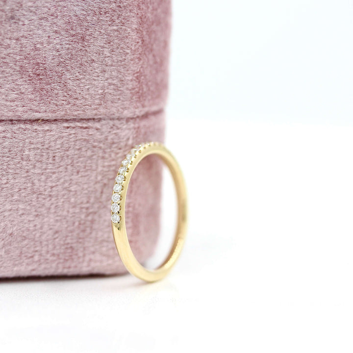 The Lauryn Wedding Band in Yellow Gold leaning against a pink velvet ring box