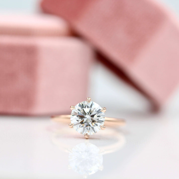 The Lola ring in rose gold in front of a pink velvet ring box