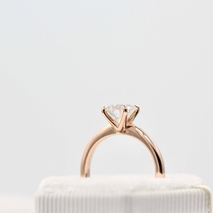 The Margot ring (round) in rose gold in a white velvet ring box