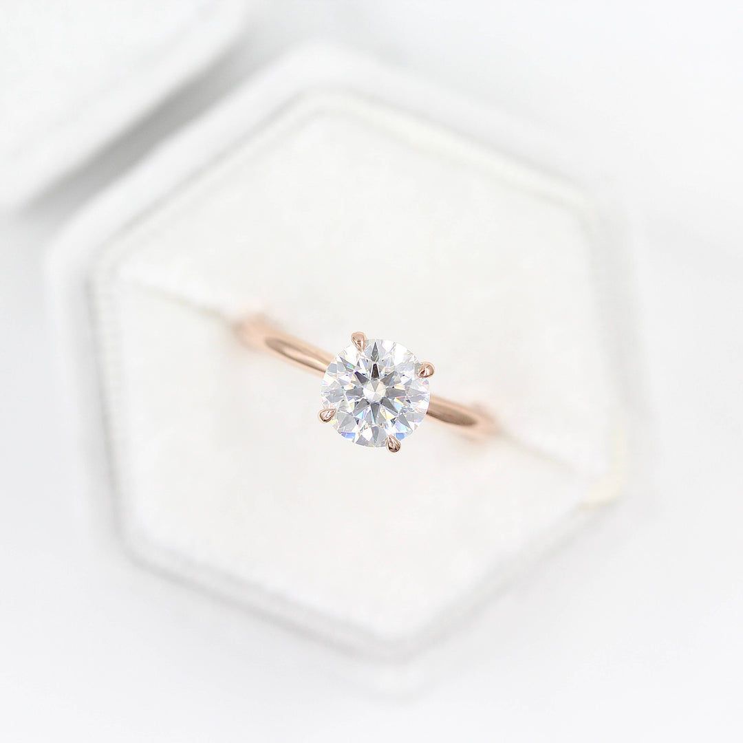 The Margot ring (round) in rose gold in a white velvet ring box