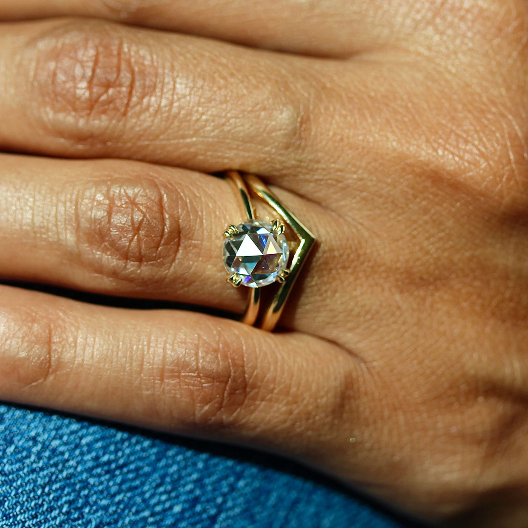 The Nora Ring (Round) in Yellow Gold stacked with the V Wedding Band in yellow gold modeled on a hand