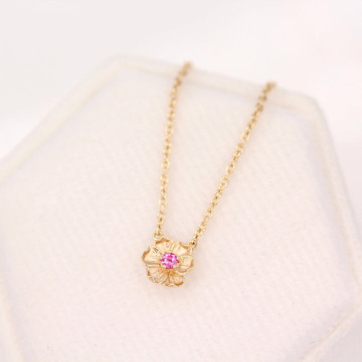 The January Birthstone Poppy Necklace with Padparadscha Sapphire in Yellow Gold atop of a white velvet ring box