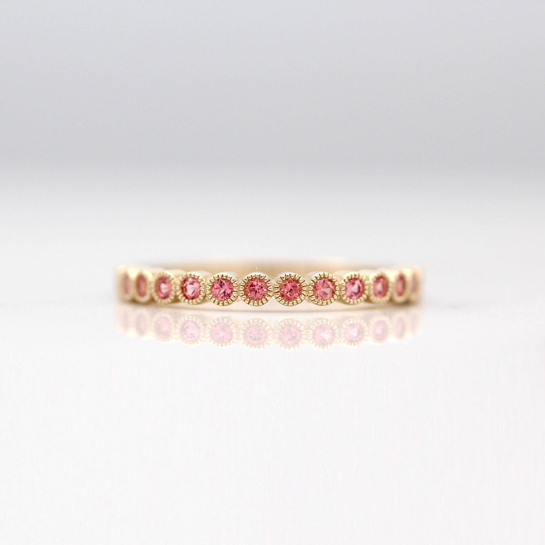 The January Florence Birthstone Wedding Band with Padparadscha Sapphire in Yellow Gold against a white background