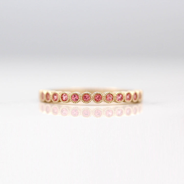 The January Florence Birthstone Wedding Band with Padparadscha Sapphire in Yellow Gold against a white background