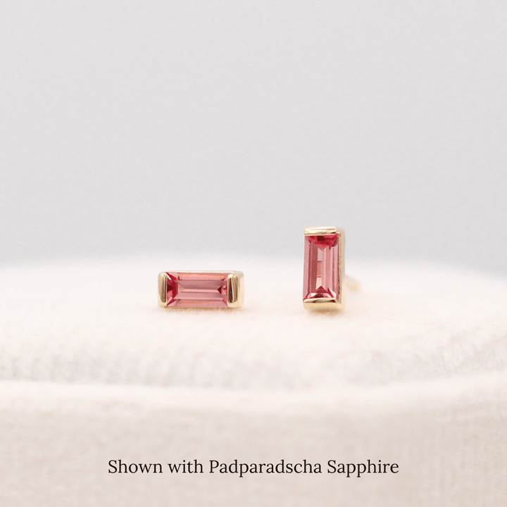 The January Baguette Birthstone Earrings with Padparadscha Sapphire in Yellow Gold atop of a white velvet ring box