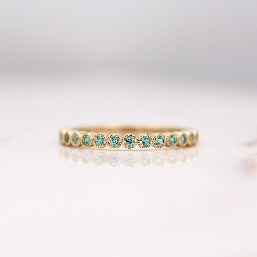 The December Florence Birthstone Wedding Band with Paraiba Spinel in Yellow Gold against a white background