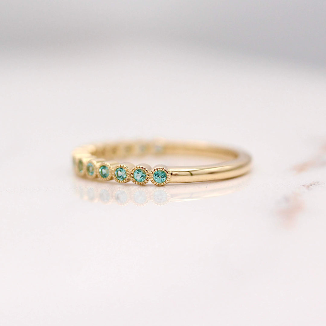 The December Florence Birthstone Wedding Band with Paraiba Spinel in Yellow Gold against a white background