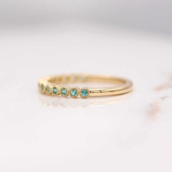 The December Florence Birthstone Wedding Band with Paraiba Spinel in Yellow Gold against a white background
