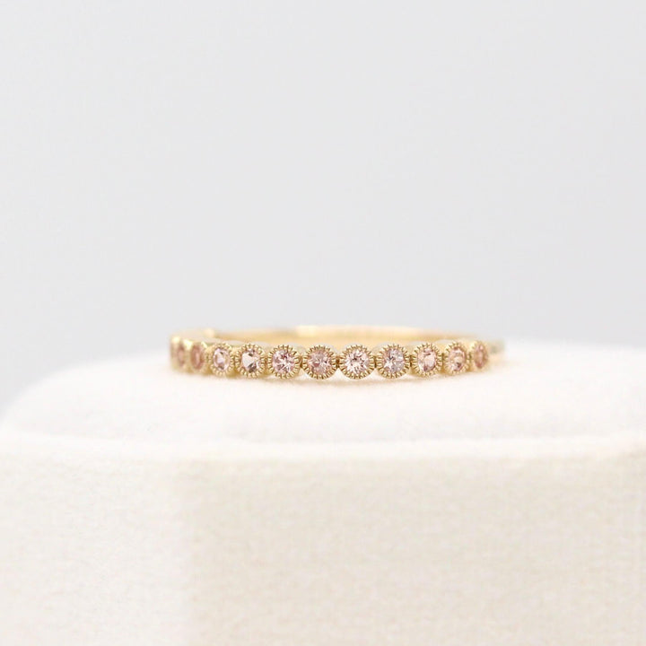 The October Florence Birthstone Wedding Band with Peachy-Pink Sapphire in Yellow Gold in a white velvet ring box