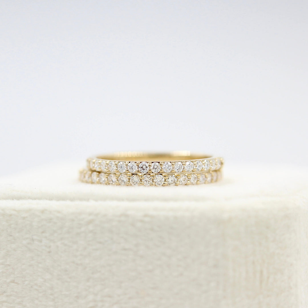 The Petite Elizabeth Wedding Band in Yellow Gold stacked with the Elizabeth Wedding Band in Yellow Gold atop of a white velvet ring box