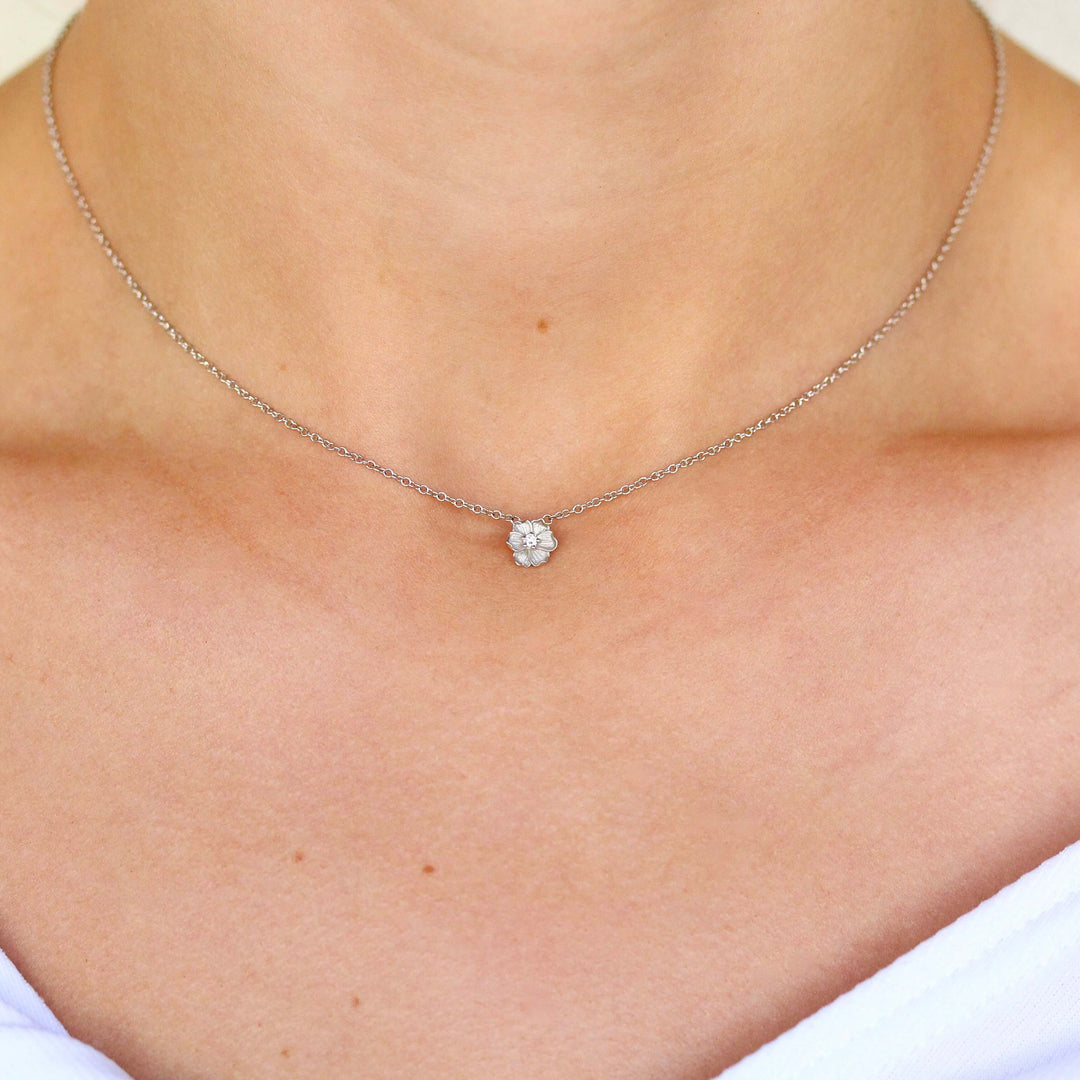 a white gold poppy necklace being worn