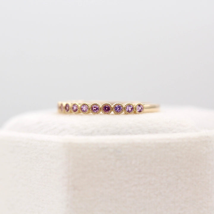 The February Florence Birthstone Wedding Band with Purple Sapphire in Yellow Gold atop of a white velvet ring box