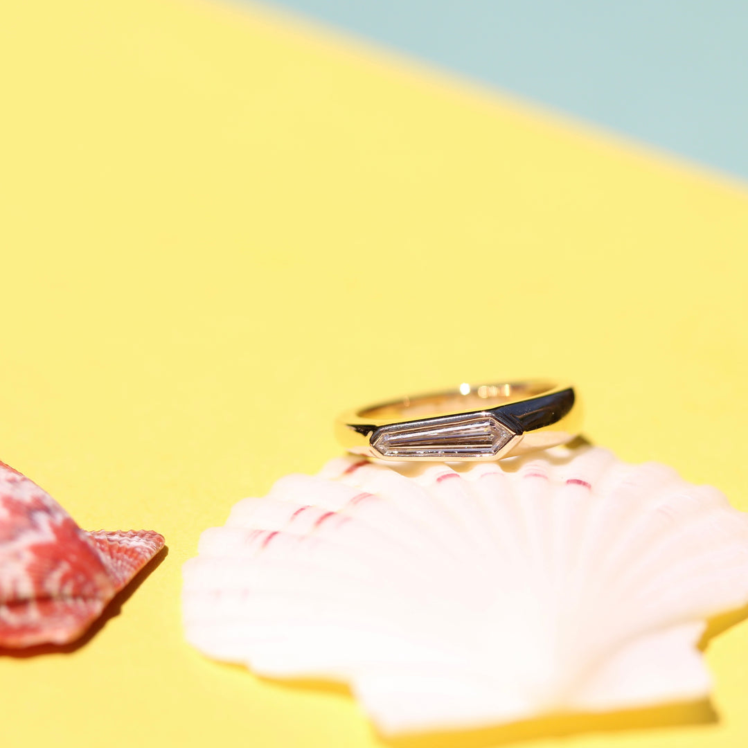 Yellow Gold Pinky ring with Shield Shape Diamond on a White Shell with Yellow Background