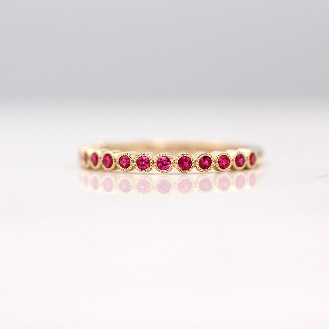 The July Florence Birthstone Wedding Band with Ruby in Yellow Gold against a white background