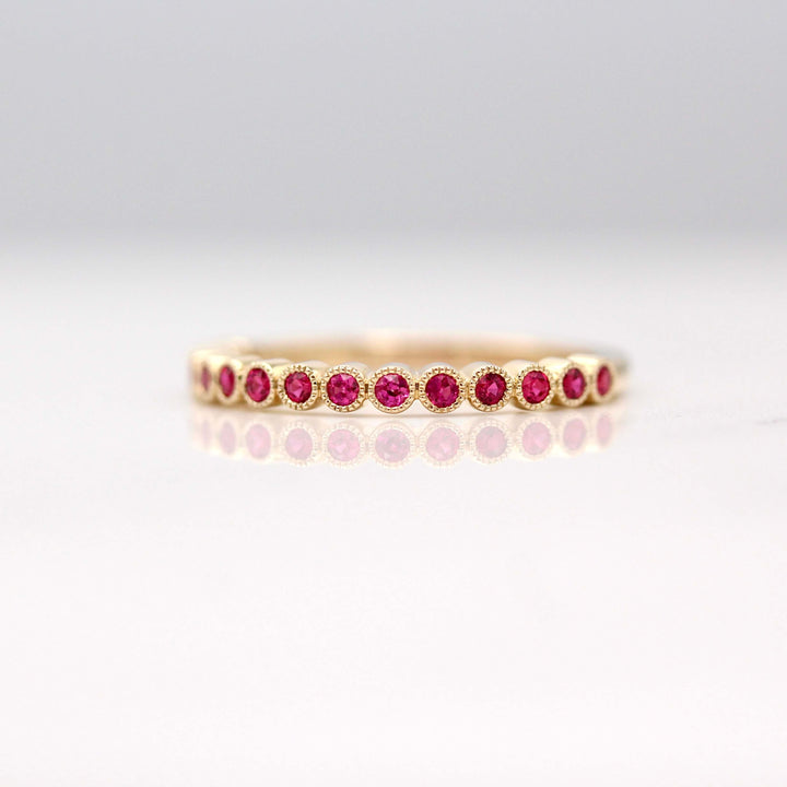 The July Florence Birthstone Wedding Band with Ruby in Yellow Gold against a white background