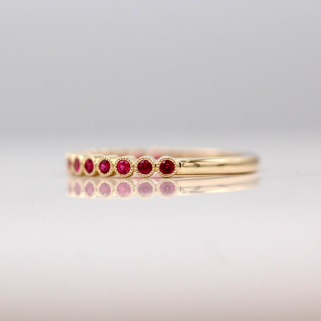 The July Florence Birthstone Wedding Band with Ruby in Yellow Gold against a white background