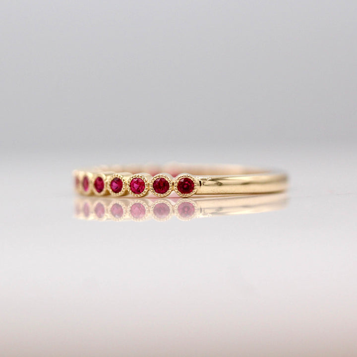 The July Florence Birthstone Wedding Band with Ruby in Yellow Gold against a white background
