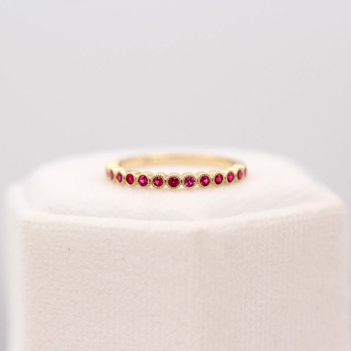 The July Florence Birthstone Wedding Band with Ruby in Yellow Gold atop of a white velvet ring box