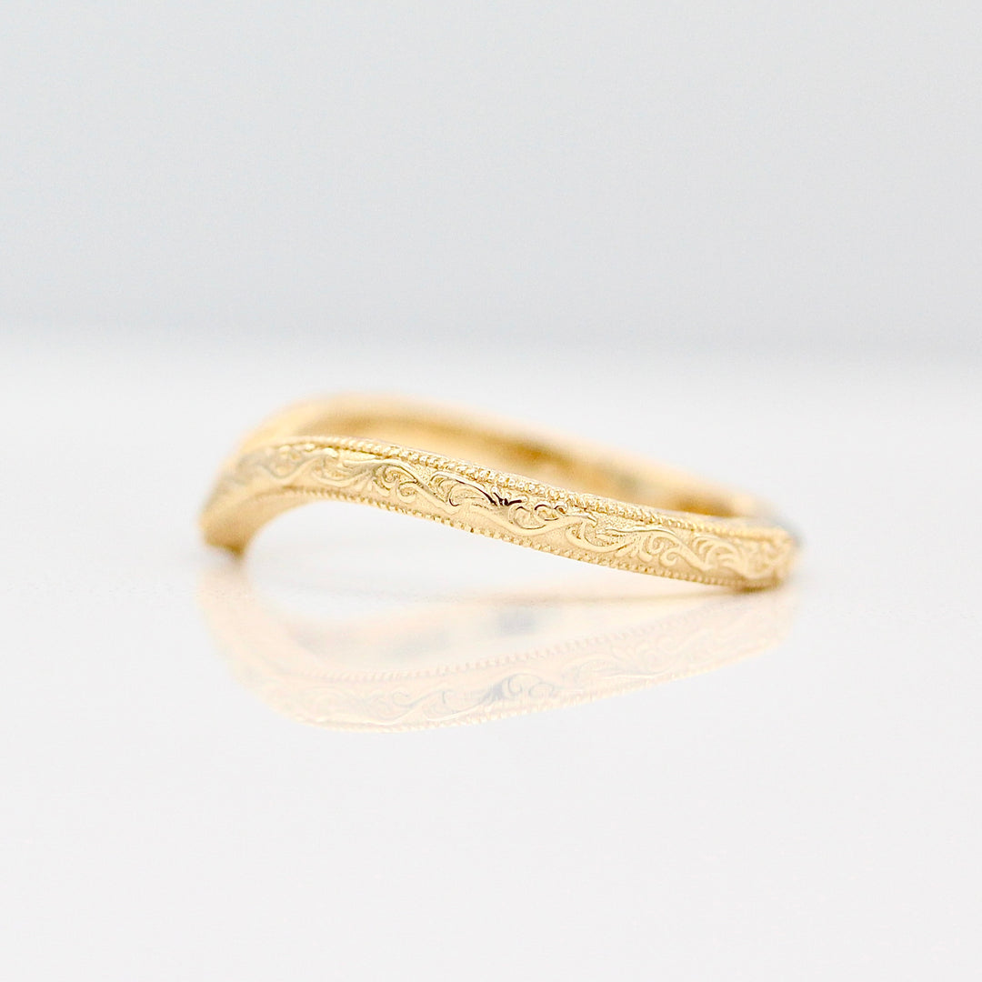 Yellow Gold Wedding Band with Intricate Engraving details agains a White Background.