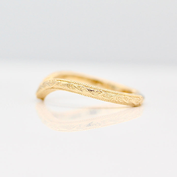 Yellow Gold Wedding Band with Intricate Engraving details agains a White Background.
