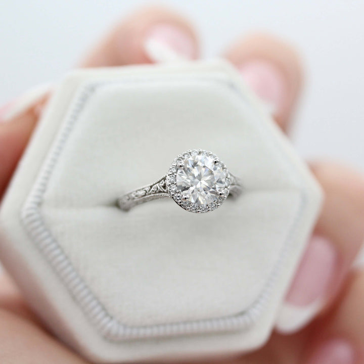 Ready to Ship Ring Colorless Moissanite / 14k White Gold / 1.5ct The Sabrina Ring (Round) in White Gold with 1.5ct Moissanite in a white velvet ring box held by a hand