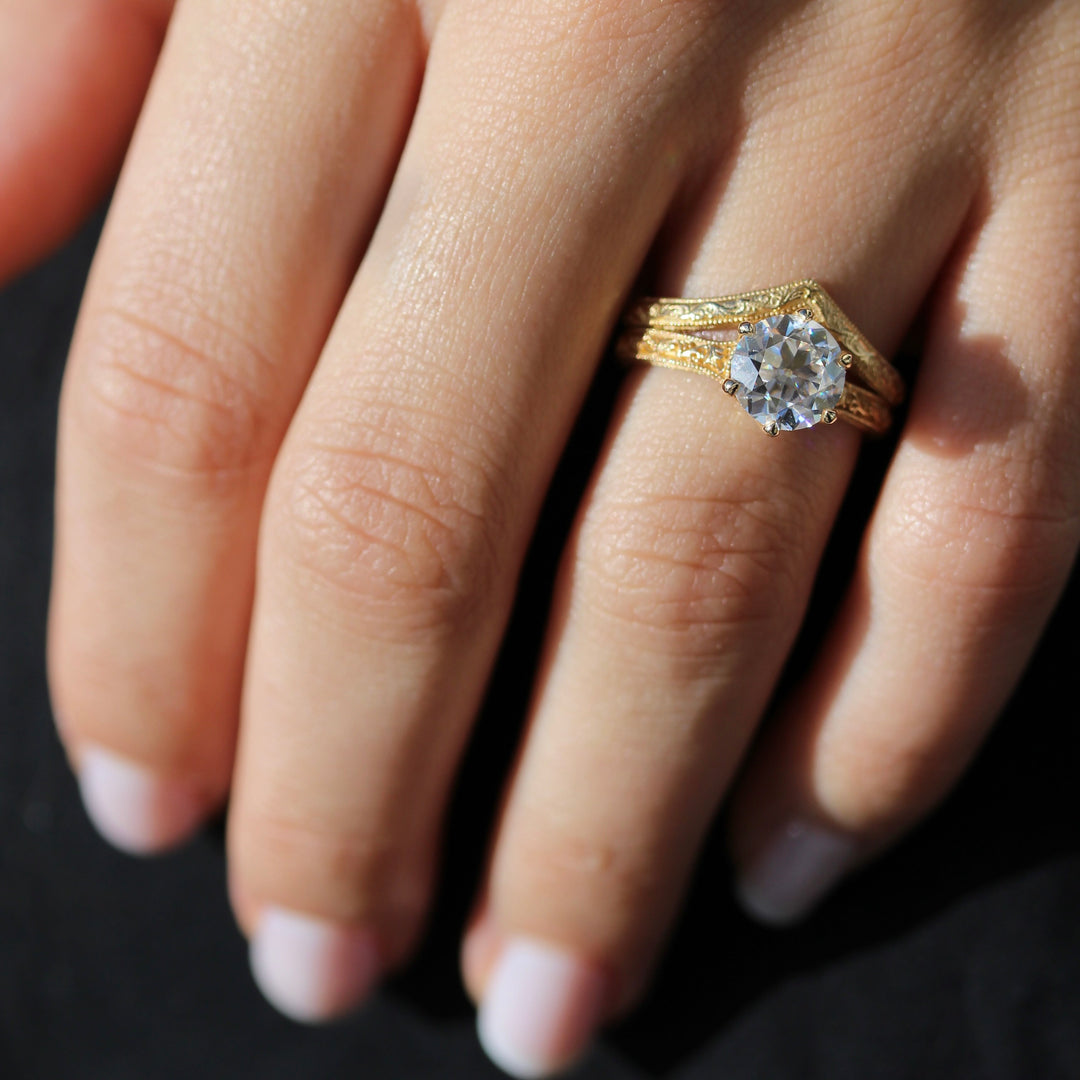 A close up of the Sabrina V Wedding Band and Sabrina Round Engagement Ring on a Hand