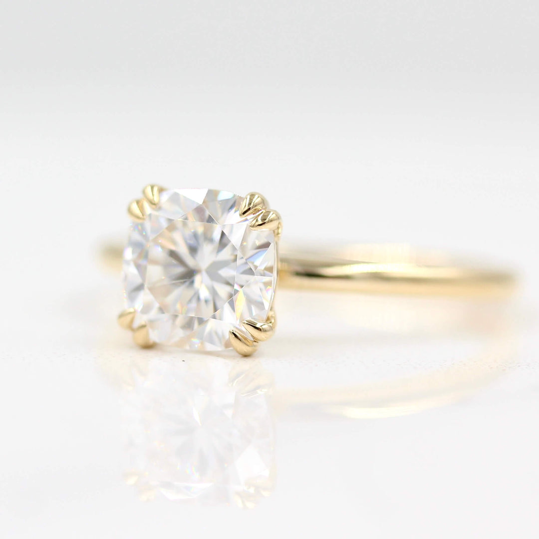 Solitaire cushion engagement ring on white background