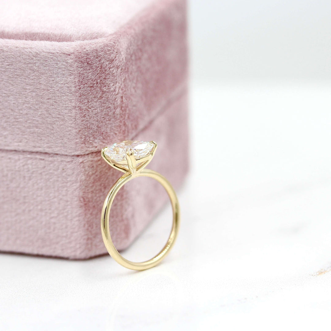 The Serena Ring (Elongated Cushion) in Yellow Gold with 3.06ct Lab-Grown Diamond leaning against a pink velvet ring box