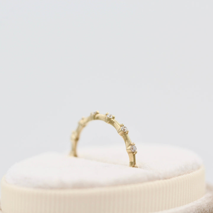 side profile of yellow gold diamond band set in a white velvet box