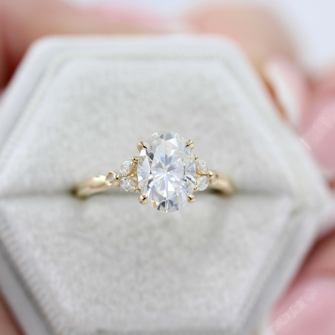 The Sophia Ring (Oval) in Yellow Gold and 2ct Moissanite in a white velvet ring box held by a hand